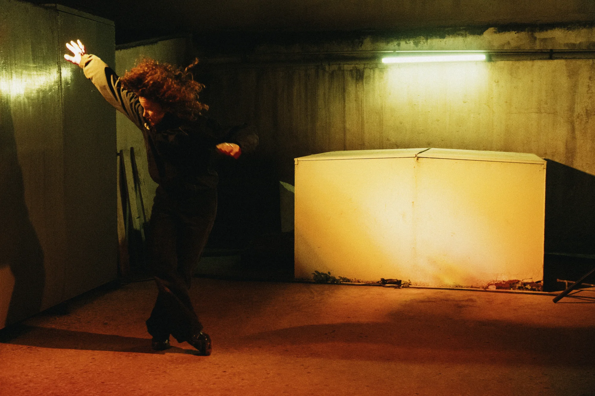 A performer turns through a wide gesture in amber light.