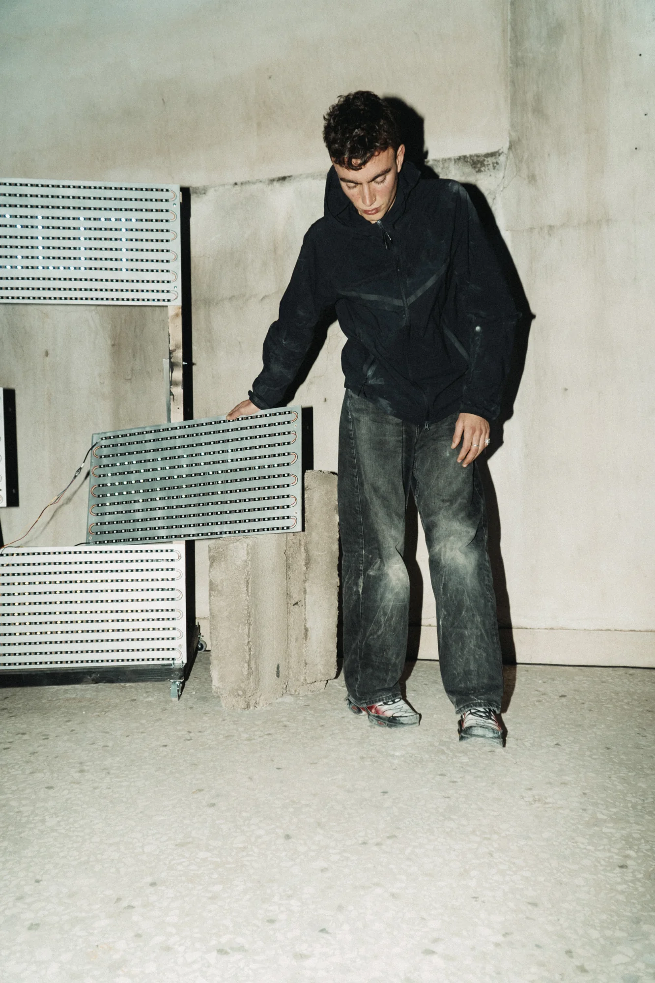 A performer lifts a portable LED panel away from the wall.