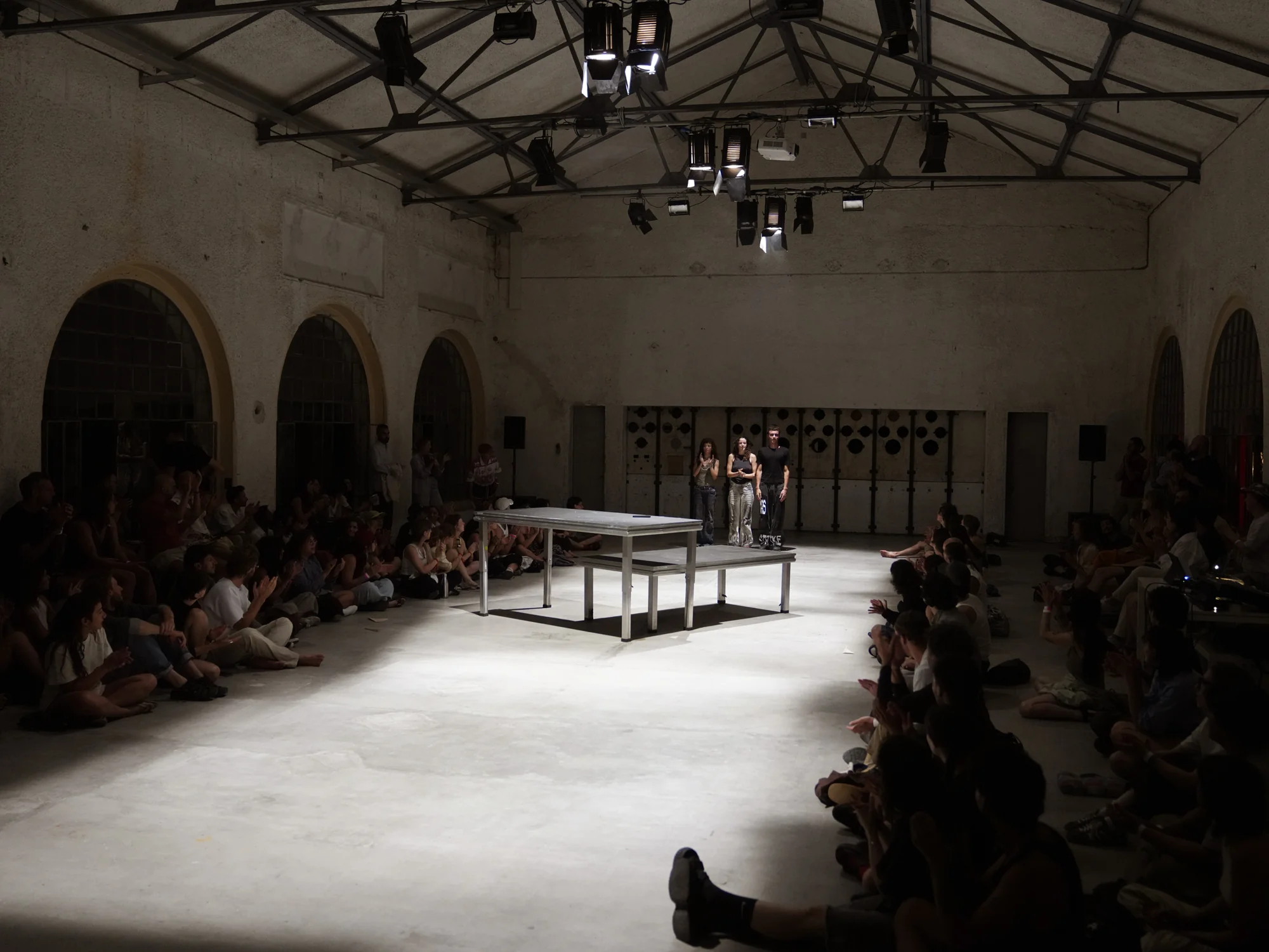 Two platforms stand in the long hall between two banks of spectators.