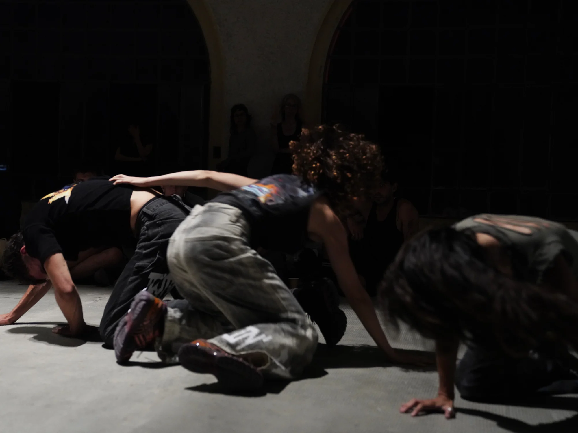 Three bodies fold towards the floor, forming a compact group.