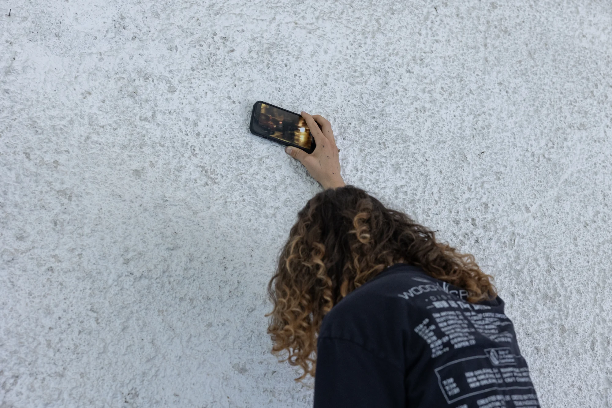 Close view of the small phone held against the wall during rehearsal.